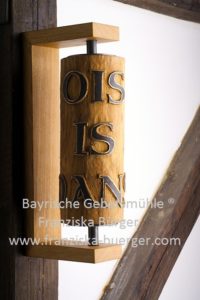 Wandgebetsmühle aus Eichenholz mit dem bayerischen Spruch „Ois is oans"